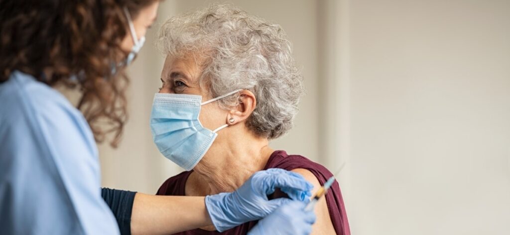 Aging adult receiving vaccine from medical professional