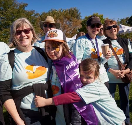 A family in matching t-shirts group-hugs at the Rise Above Seizures walk.